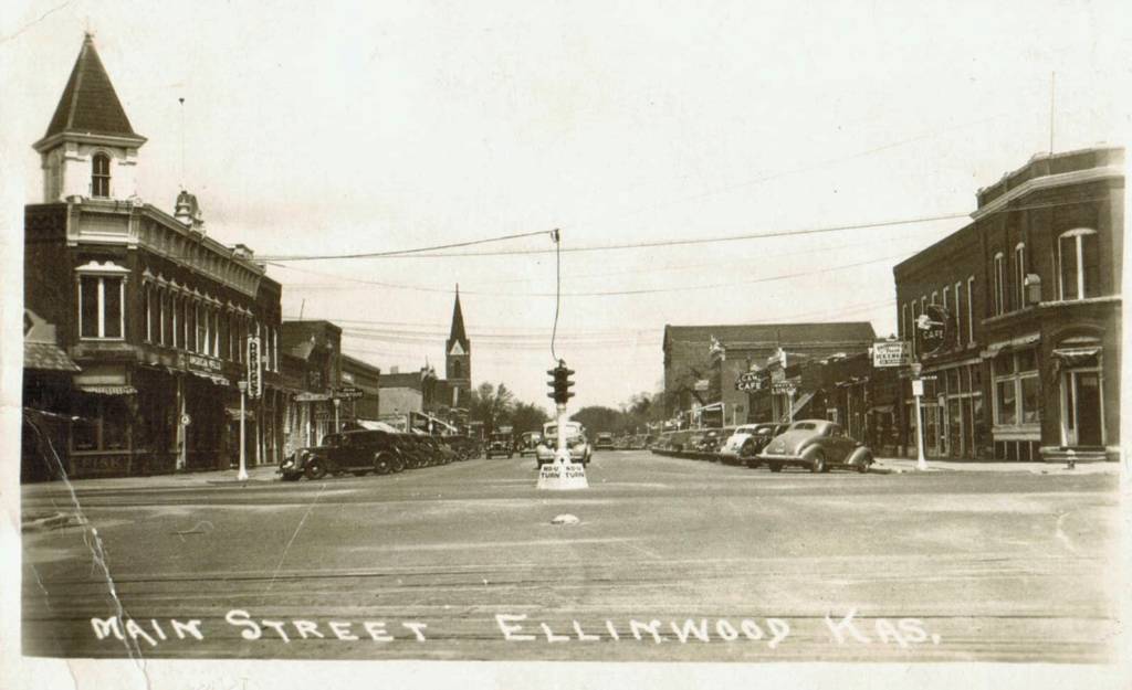 Historical photos of Ellinwood's Main Street. Cars are seen parked along the downtown building and a stoplight is hanging in the intersection.