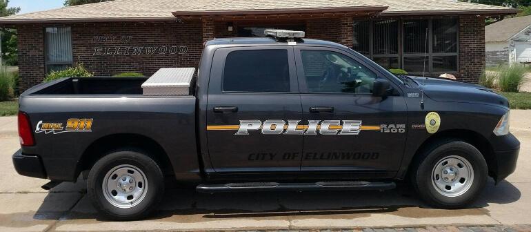 Side view of the Ellinwood Police Truck parked in front of the Ellinwood City Building
