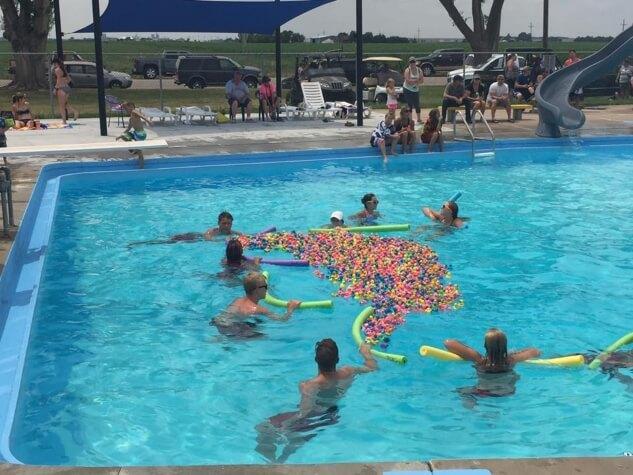 Lifeguards in the city pool surrounding a large amount of rubber ducks with pool noodles