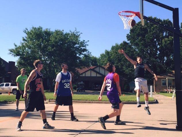 Five young men playing an outdoor game of basketball